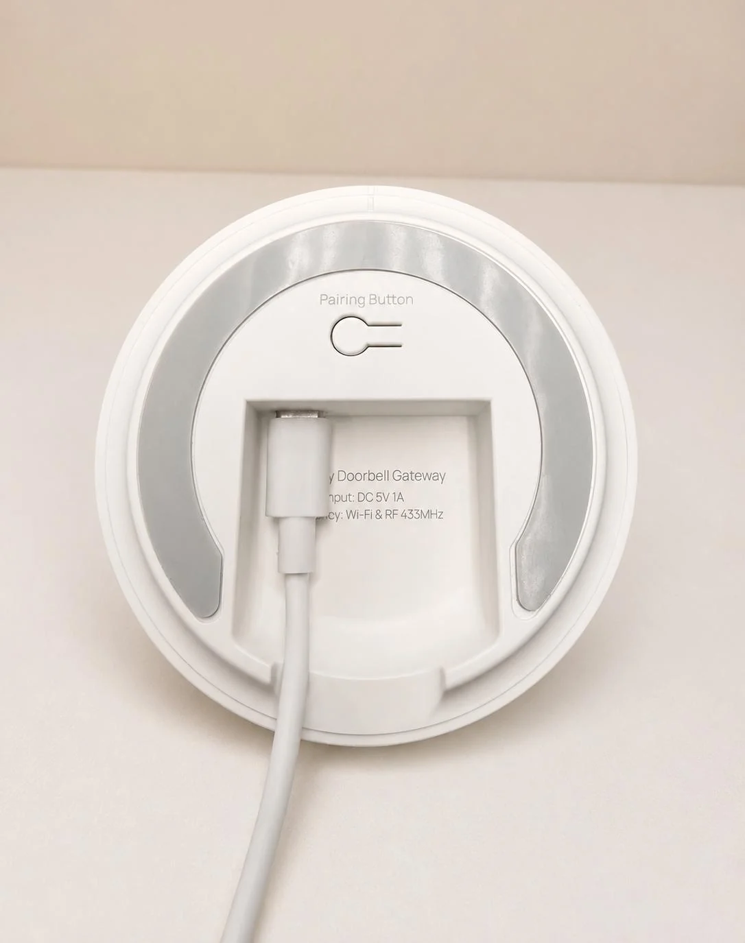 USB-C cable connected beside the pairing button on the bottom of the Mini Alarm Hub